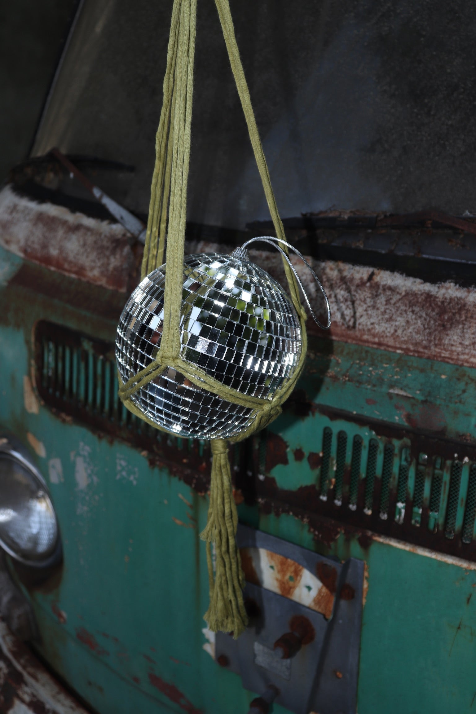 Someone holding the Chartreuse Disco Ball Hanger with Disco Ball in front of a vintage teal Volkswagen bus.