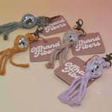 All of the Mini Macrame Disco Ball Keychain on a pink and yellow background.