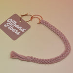 The blush Boho Moon Charm Macrame 12 in. Bookmark on a light pink and yellow background.