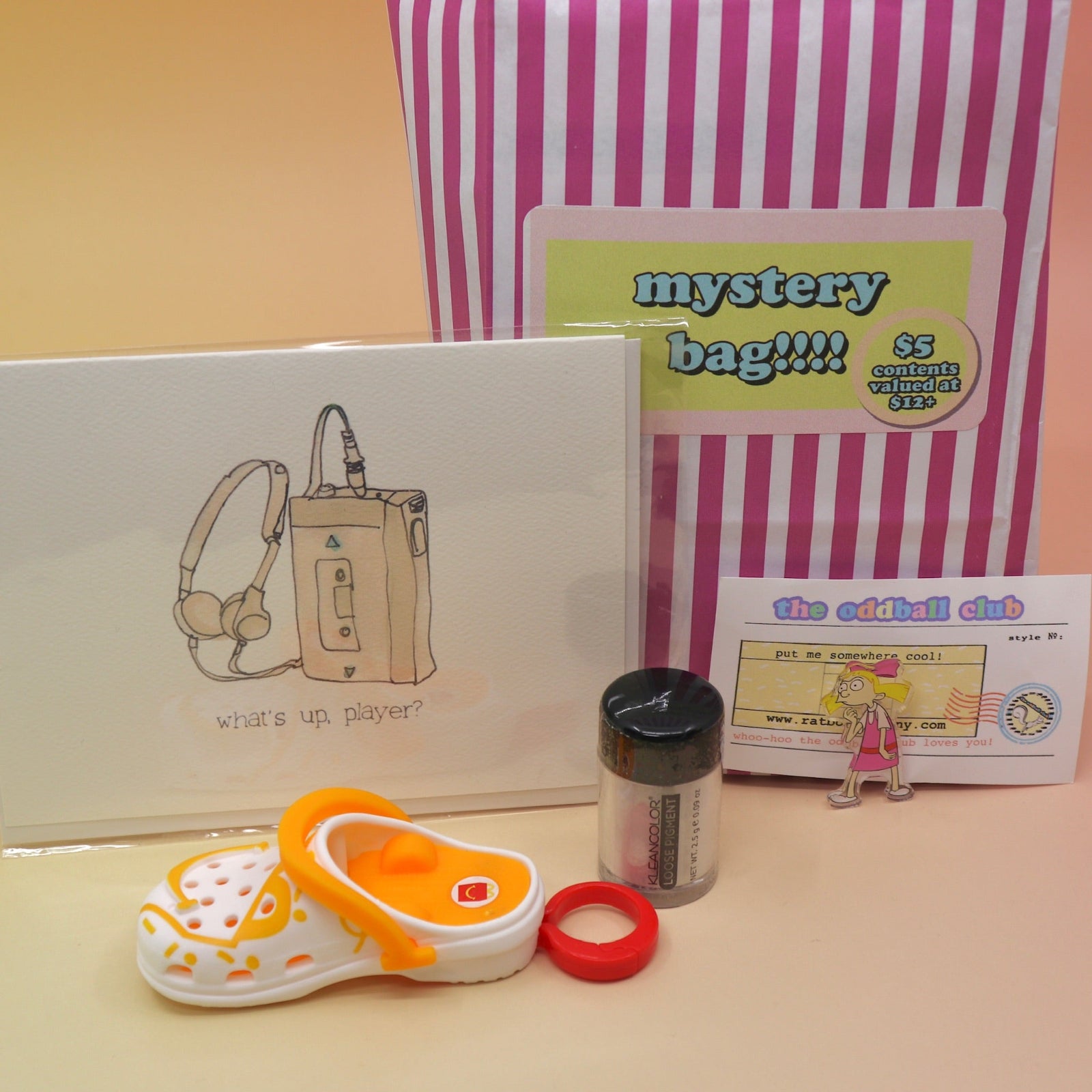 The 5 Dollar Blind Mystery Bag with its contents out on a pink and orange background.