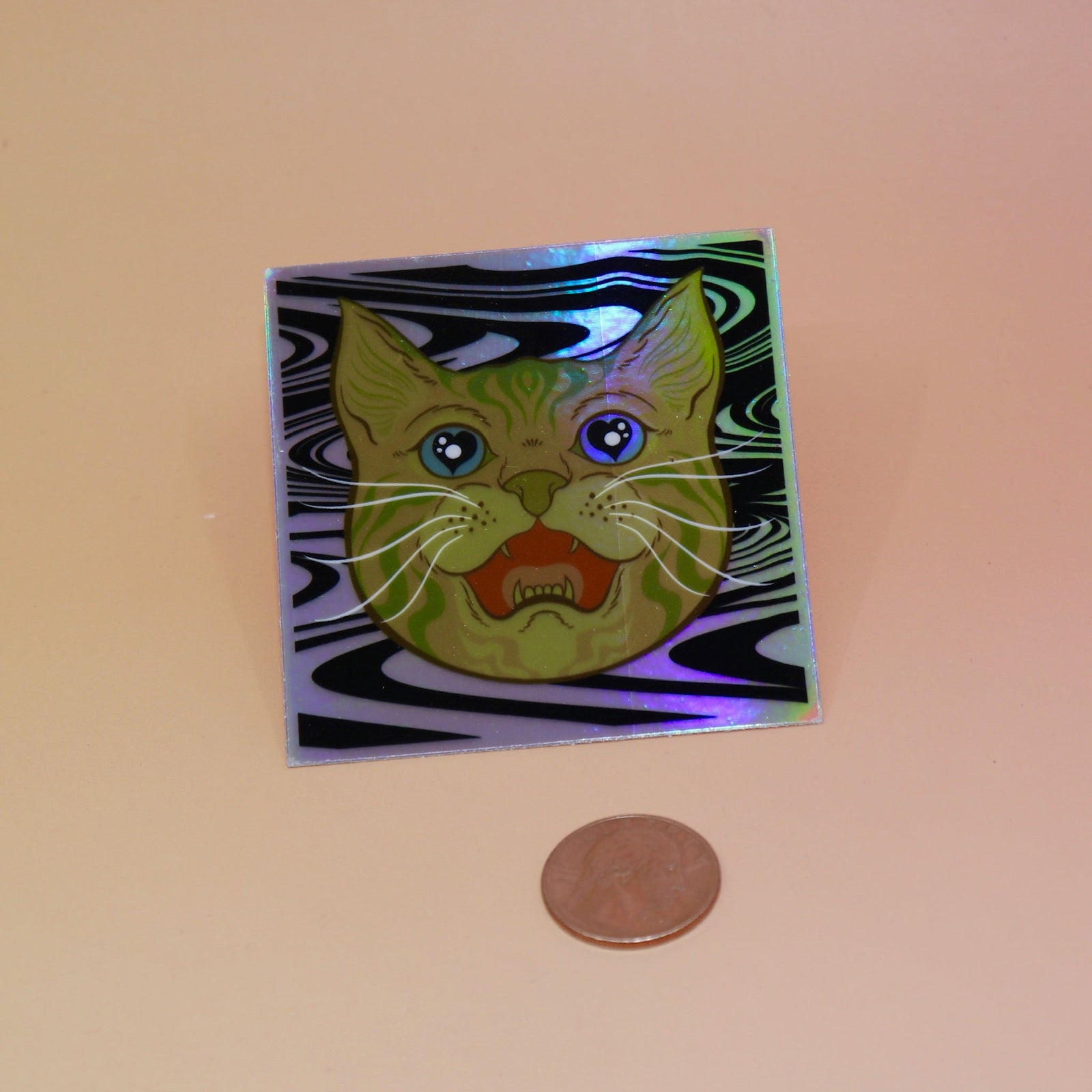 The Cozmik Love Cat 3" Holographic Vinyl Sticker next to a quarter on a light pink background.