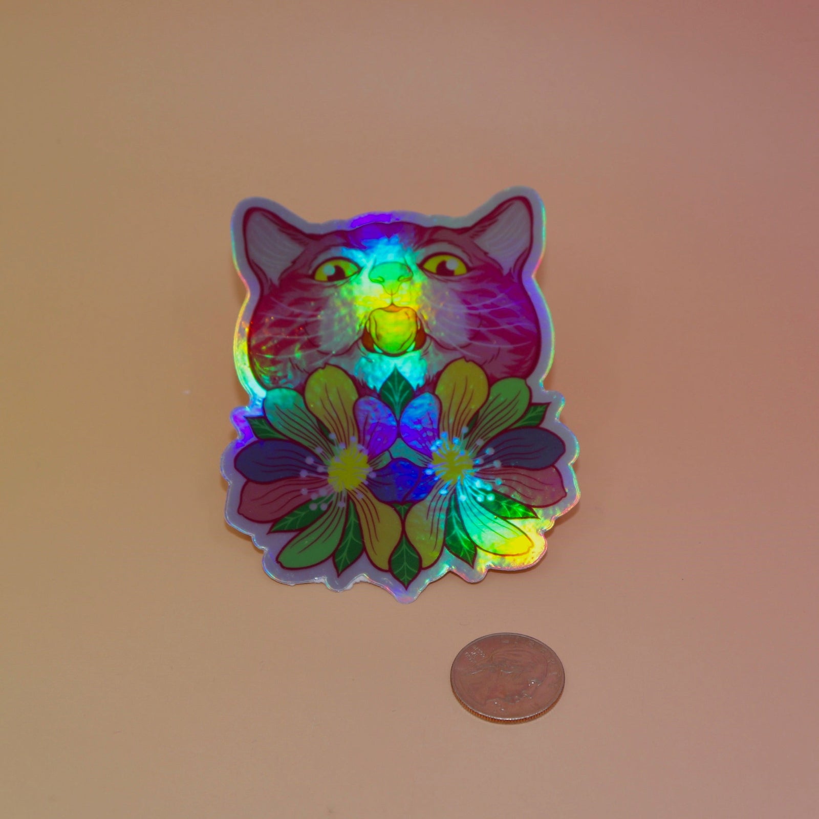 The Sapphic Flower Kitty 4" Holographic Vinyl Sticker next to a quarter on a light pink background.