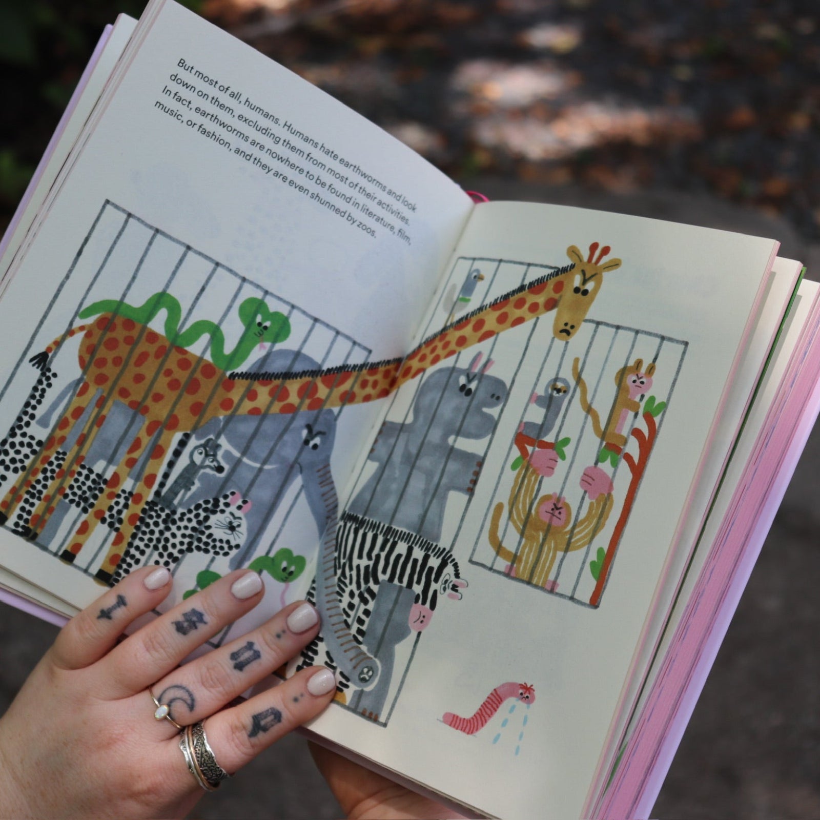 Someone showing one of the pages of the Unfortunate Life of Worms Hardcover Book.