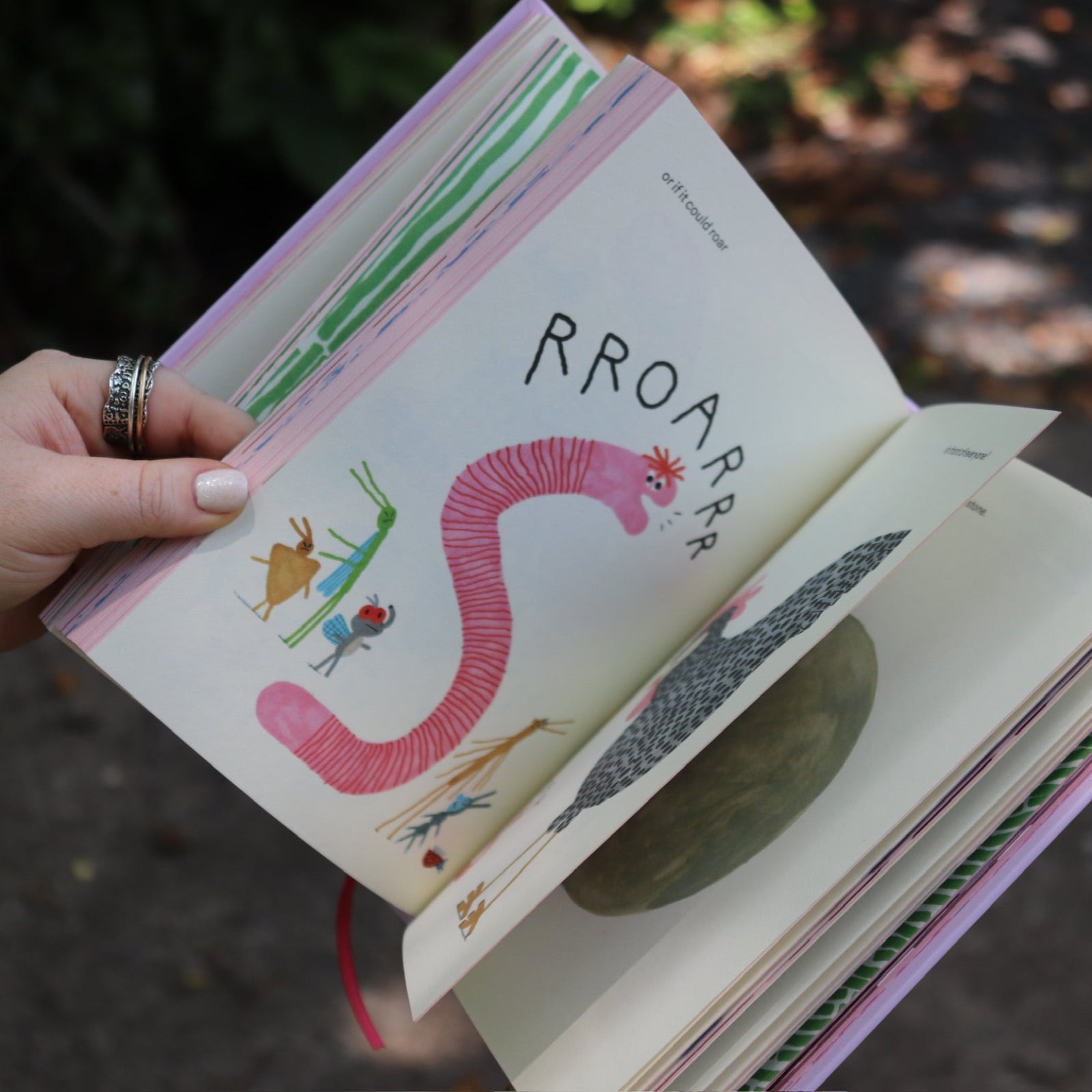 Someone flipping through the pages of the Unfortunate Life of Worms Hardcover Book.