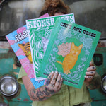 A woman holding all three of the Cat Champion cat coloring books.