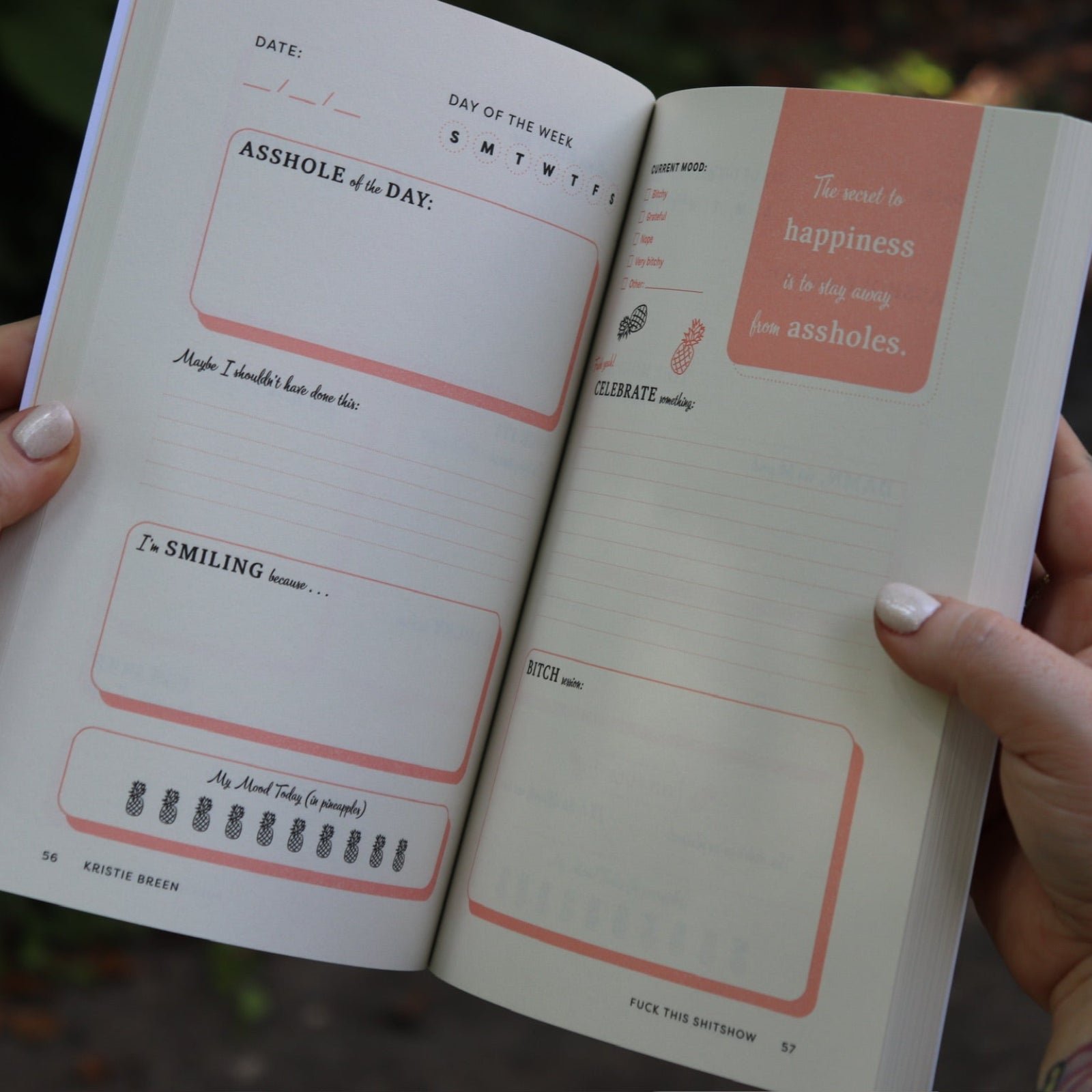 Someone holding the F*ck This Sh*tshow Gratitude Journal open to show off the pages.