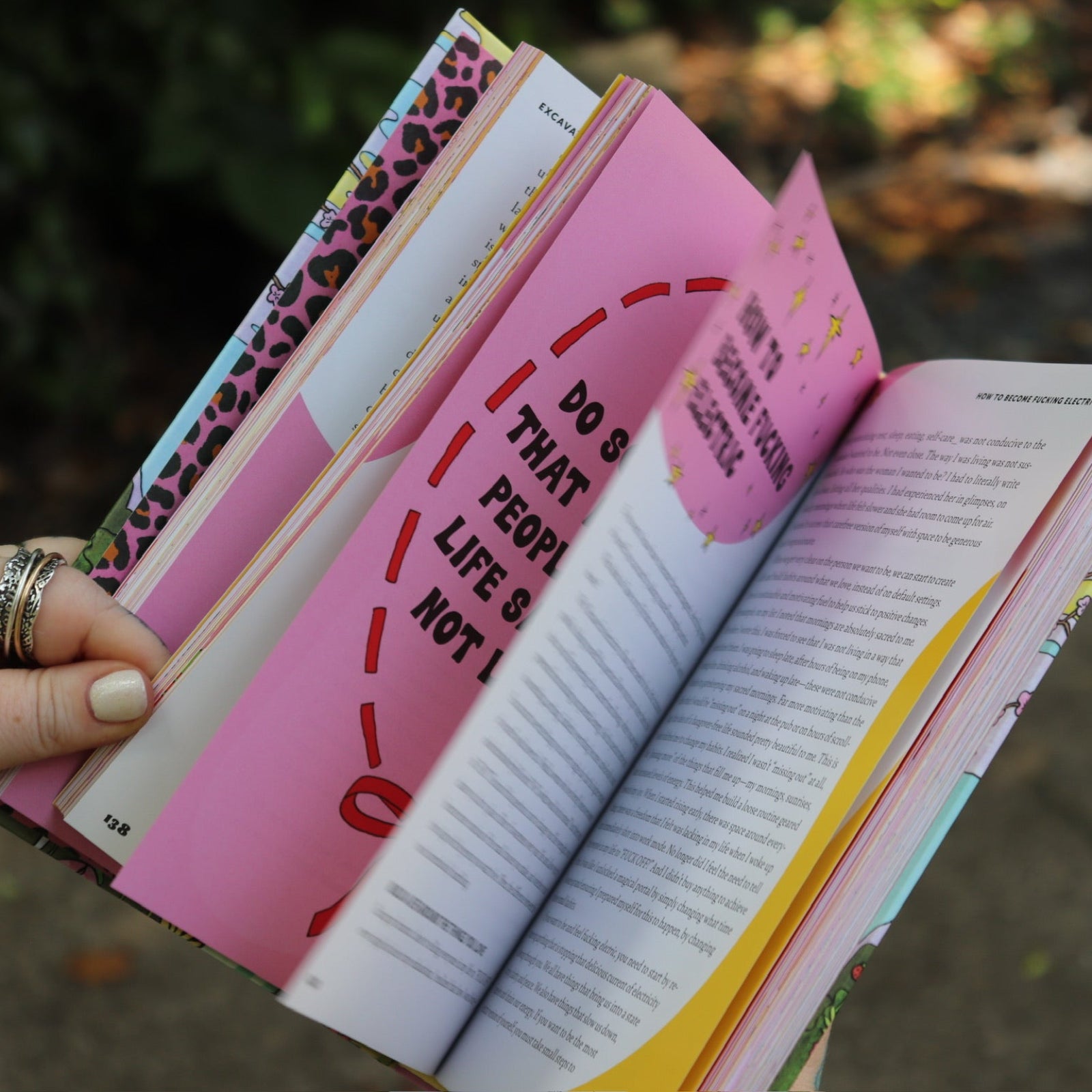 A woman holding the Women Living Deliciously Hardcover Book open to show off its pages.