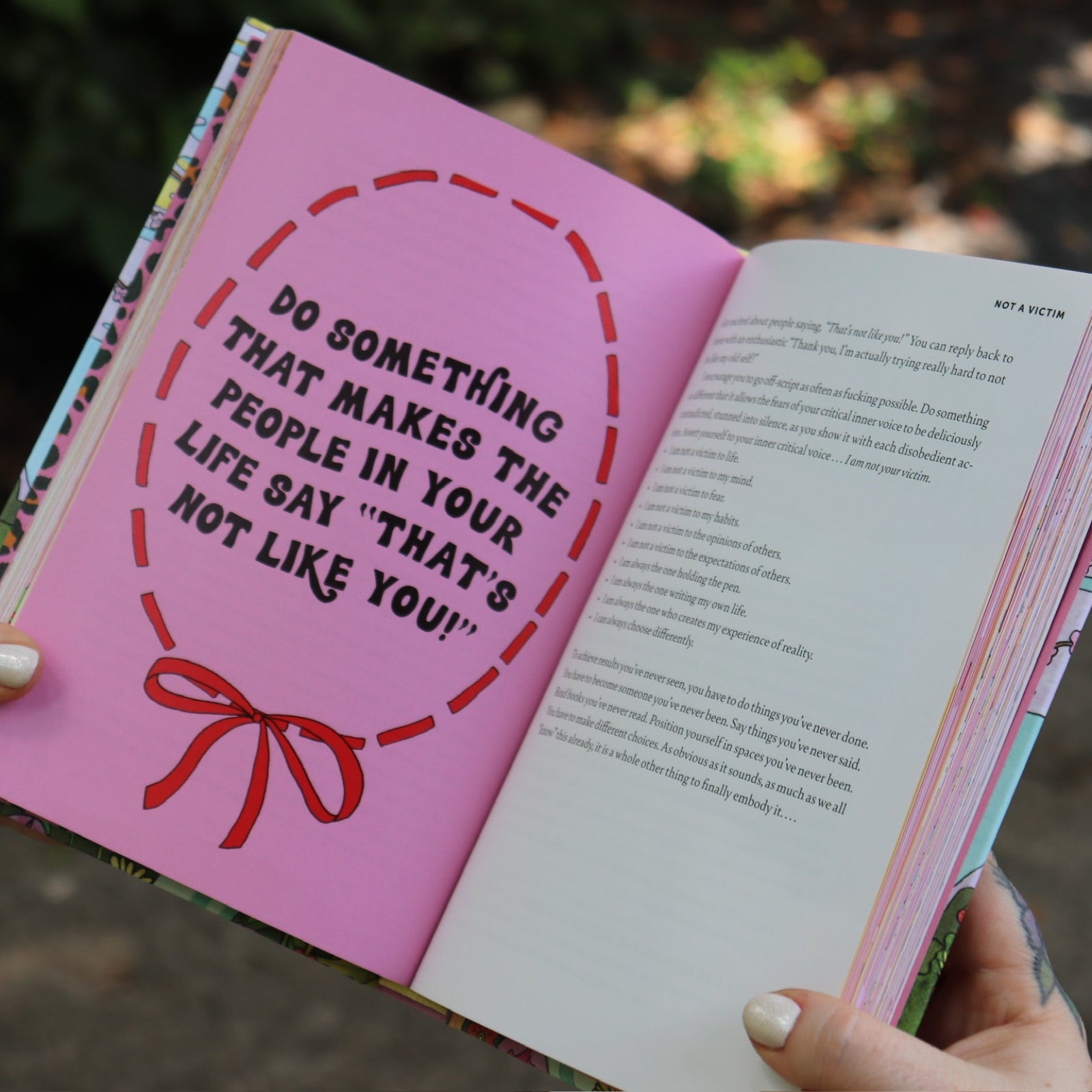 A woman holding the Women Living Deliciously Hardcover Book open to show off its pages.
