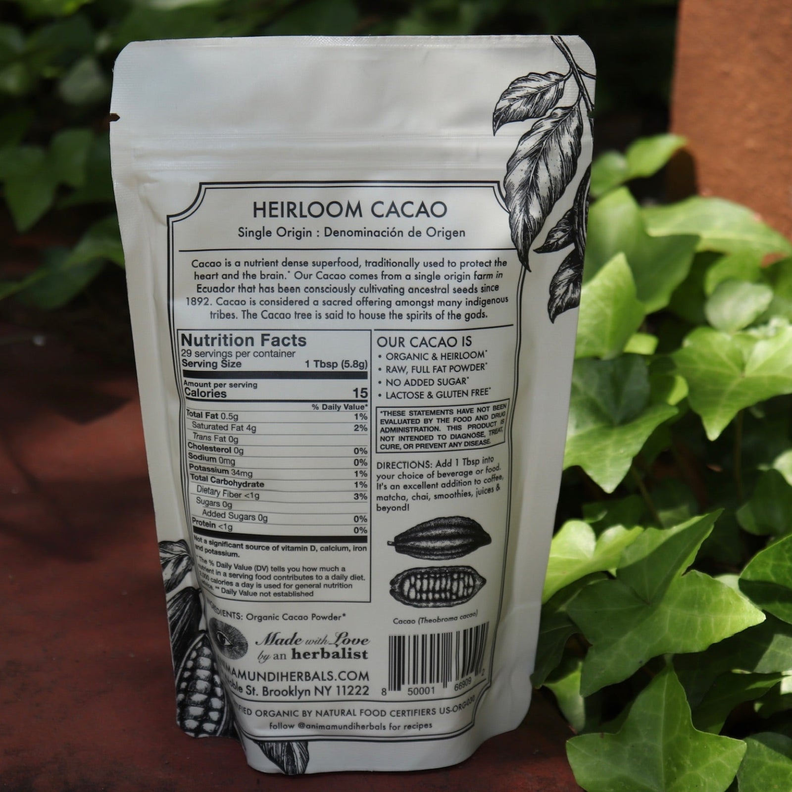 The back of the Heirloom Cacao - Ancestral Cacao Powder on a rusty red surface next to ivy.