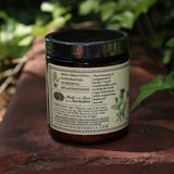 The side of the Happiness Herbal “Coffee” Powder on a rusty red surface surrounded by green ivy.