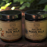 The Golden Moon Milk - 5oz Blue Lotus Vanilla Powder and Golden Sun Milk Powder on a red surface next to ivy.