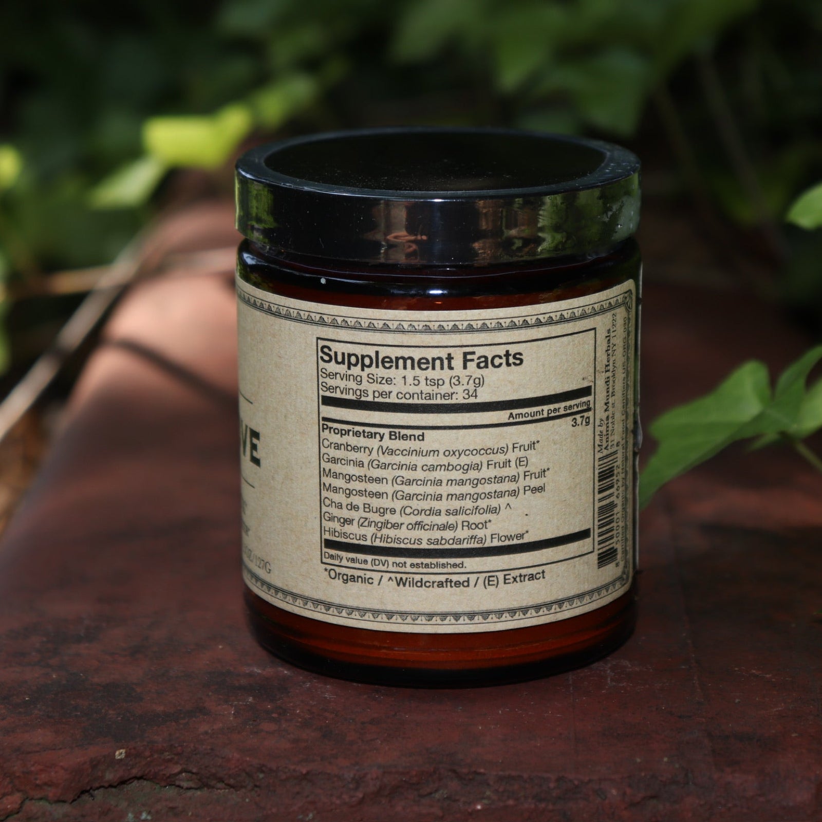 The back of the Belly Love - Metabolism Harmonizer 4.5 oz Powder on a rusty red surface surrounded by green ivy.