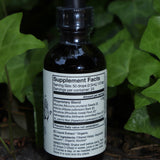 The Happiness Tonic - 2 fl. oz. Adaptogenic Spirit Tonic on a graphite surface in front of a patch of ivy.