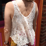 A woman wearing the beige Crochet Hollow Knit Vest with Leaf Texture with tie-dye bottoms.