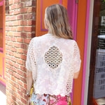 A woman wearing the beige Lace Open Front Cardigan with Batwing Sleeves with tie-dye bottoms and top.