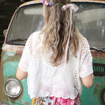 A woman wearing the white Lace Open Front Cardigan with Batwing Sleeves with tie-dye bottoms and crochet top.