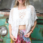 A woman wearing the white Lace Open Front Cardigan with Batwing Sleeves with tie-dye bottoms and crochet top.