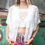 A woman wearing the white Lace Open Front Cardigan with Batwing Sleeves with tie-dye bottoms and crochet top.