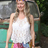 A woman wearing the white Crochet Hollow Knit Vest with Leaf Texture with tie-dye bottoms.