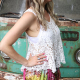 A woman wearing the white Crochet Hollow Knit Vest with Leaf Texture with tie-dye bottoms.