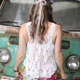 A woman wearing the white Crochet Hollow Knit Vest with Leaf Texture with tie-dye bottoms.
