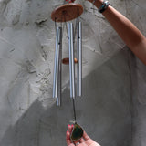 Someone holding the Woodstock Agate Celtic Chime in front of a concrete wall.