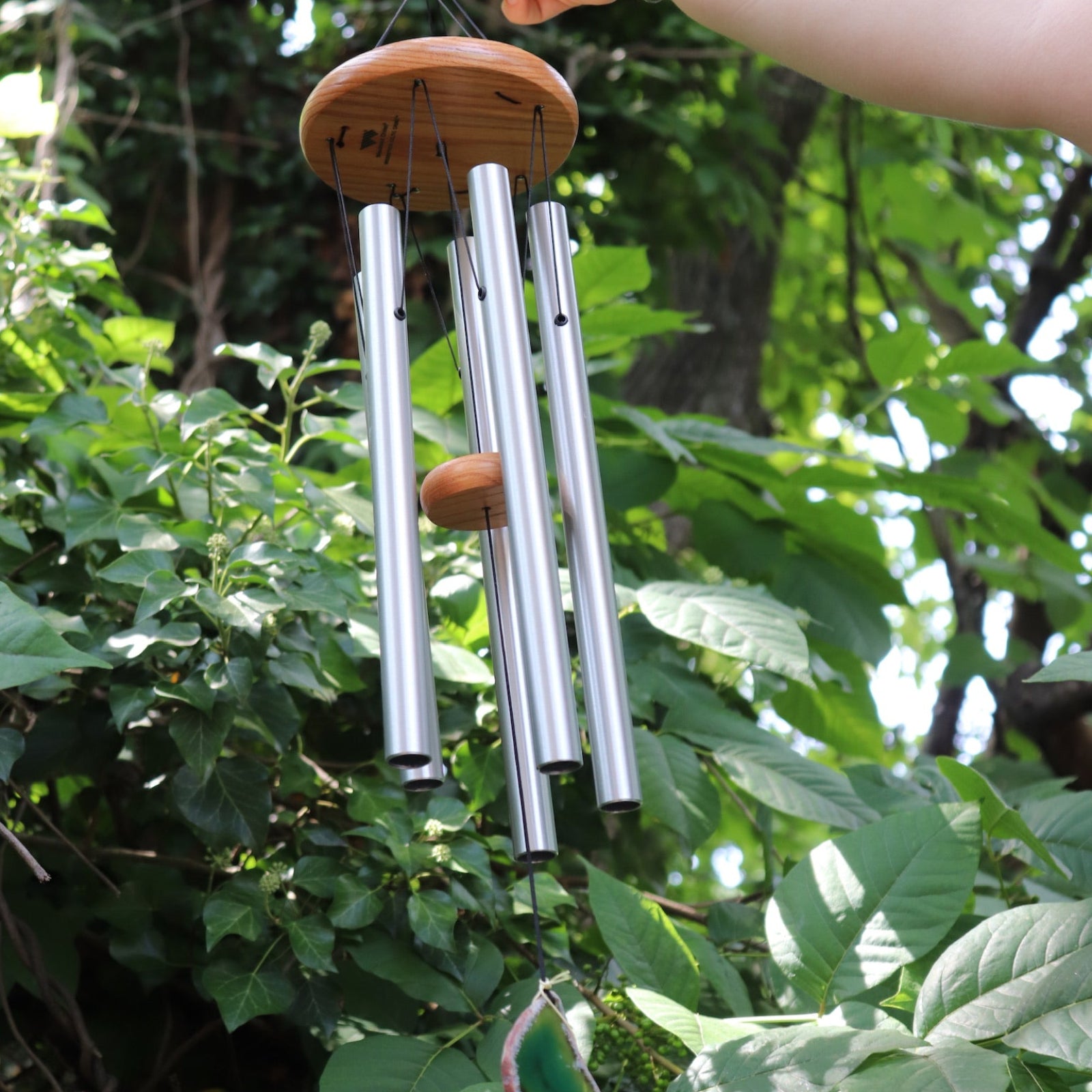 Someone holding the Woodstock Agate Celtic Chime in front of bushes.