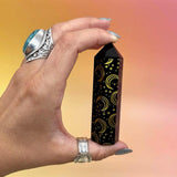 Hand holding a wooden pentacle with star and moon designs against a gradient background