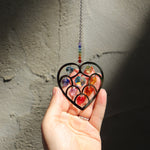 Someone holding the Heart of Hearts Chakra Ornament in the sunlight.