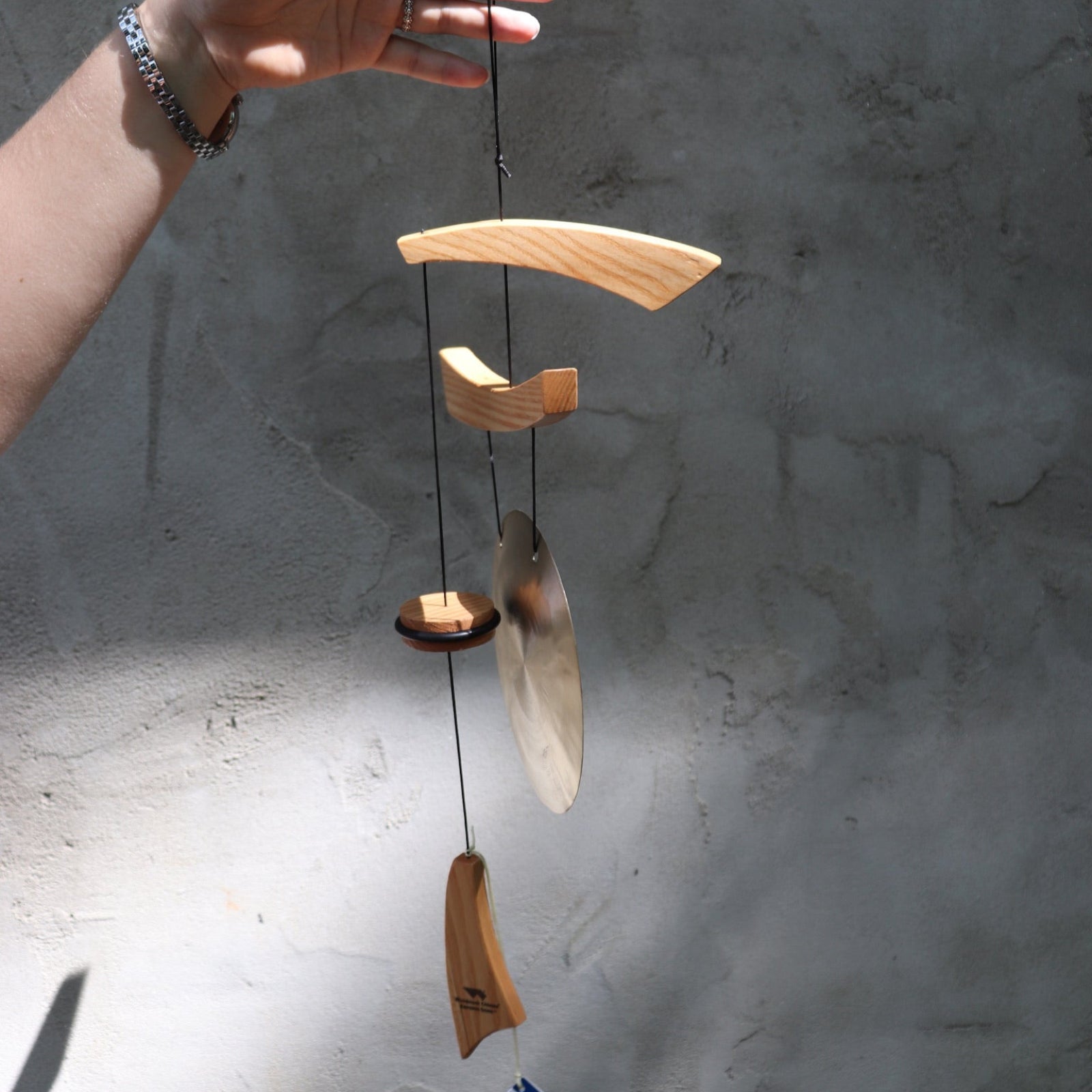 Someone holding the Small Emperor Gong Wind Chime in front of a white wall.