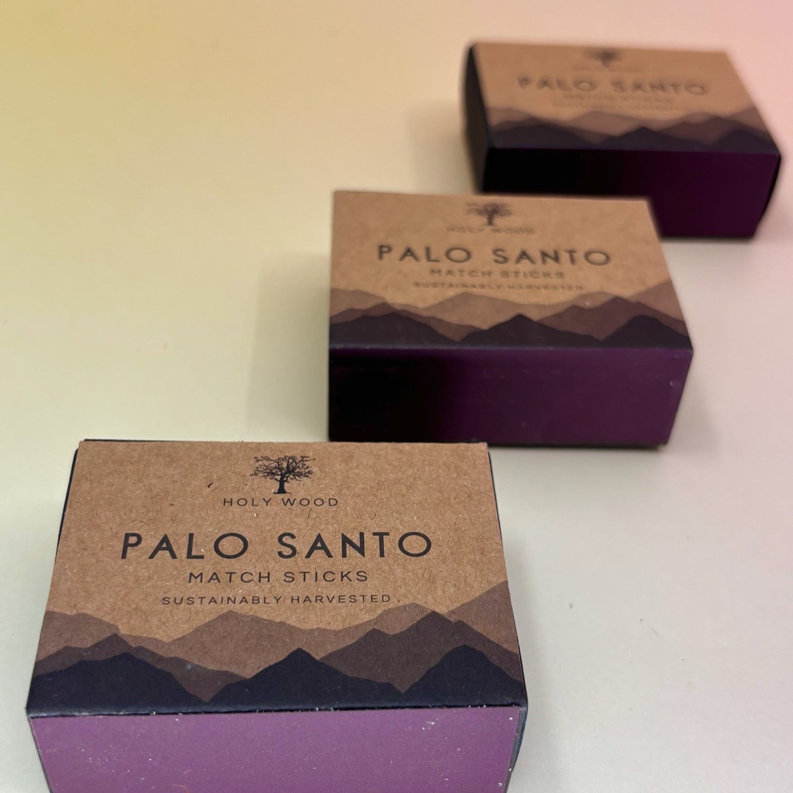 Three Palo Santo Matchstick boxes on a pale pink and yellow background.