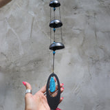 Someone holding the Turquoise Woodstock Temple Bells in front of a white wall.