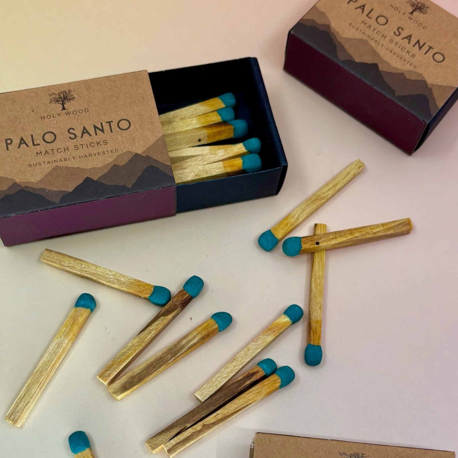 Three Palo Santo Matchstick boxes on a pale pink and yellow background.