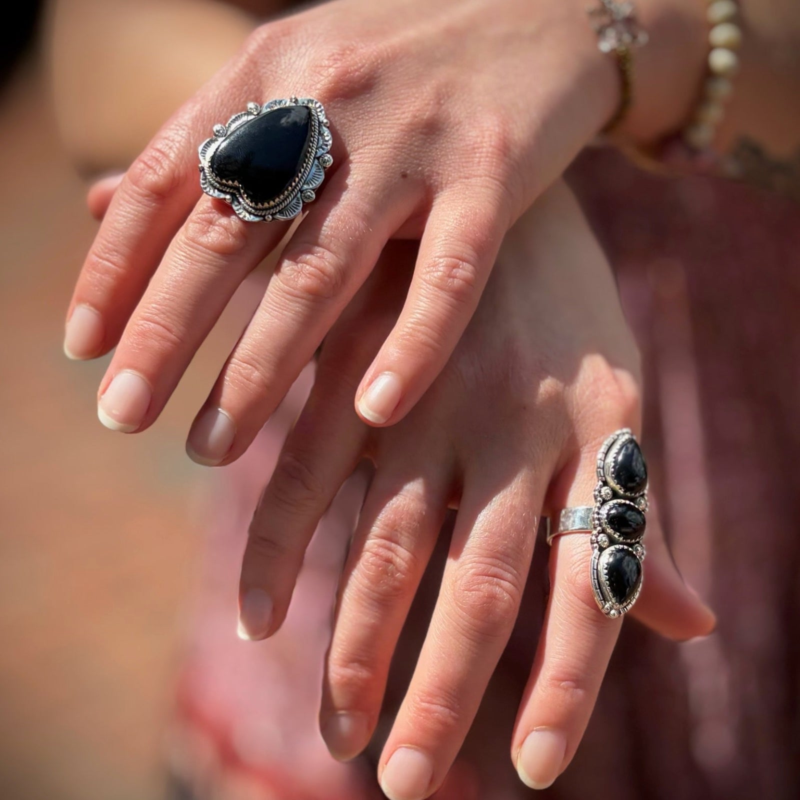 Someone wearing the Three Stone Black Onyx Sterling Silver Adjustable Ring and the Black Onyx Crystal Heart Adjustable Sterling Silver Ring.