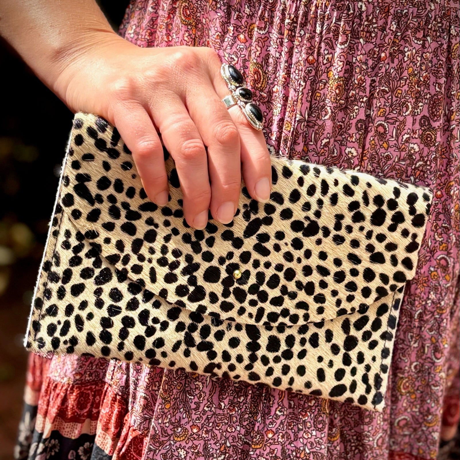 Some holding the Tiny Spotted Hair on Hide Envelope Pouch Clutch next to their dress.