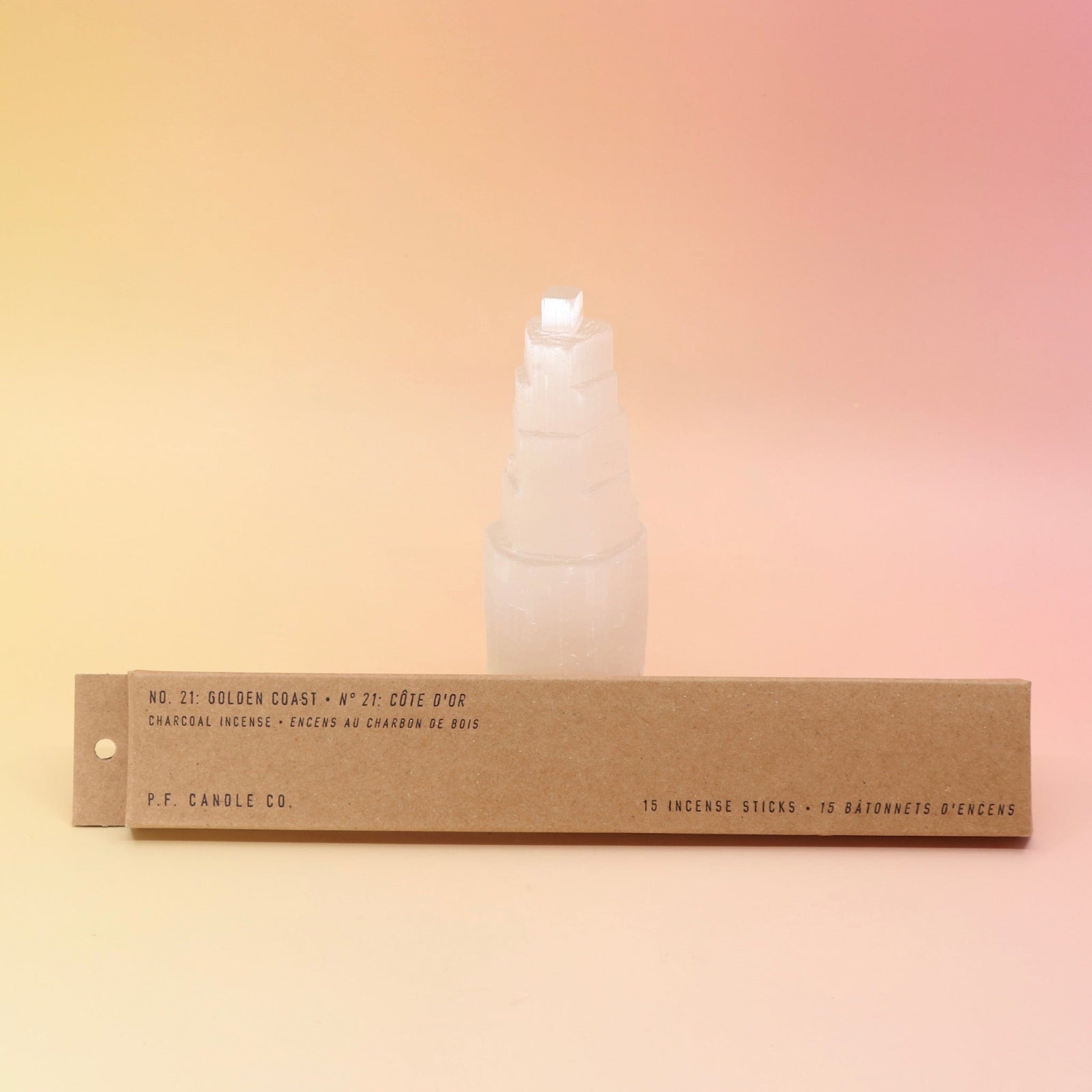 The P.F. Candle Co. Golden Coast Incense in front of a selenite tower on a pink and yellow background.