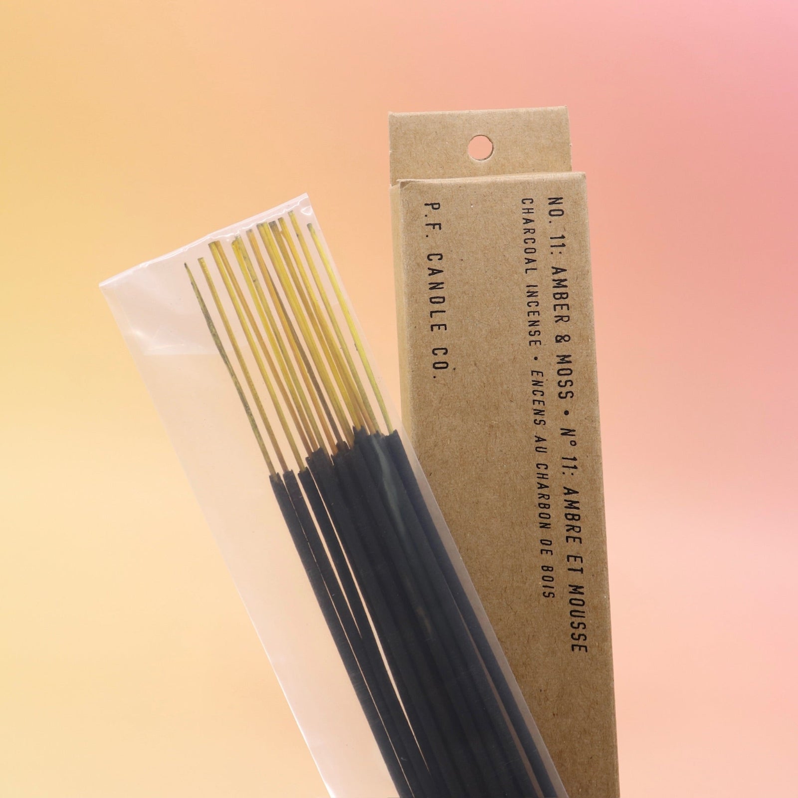 The Amber & Moss Incense - Pack of 15 from P.F. Candle Co. on a pink and yellow background.