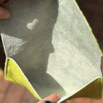 Someone holding the Chartreuse Hair on Hide Envelop Pouch Clutch open to show the inside.