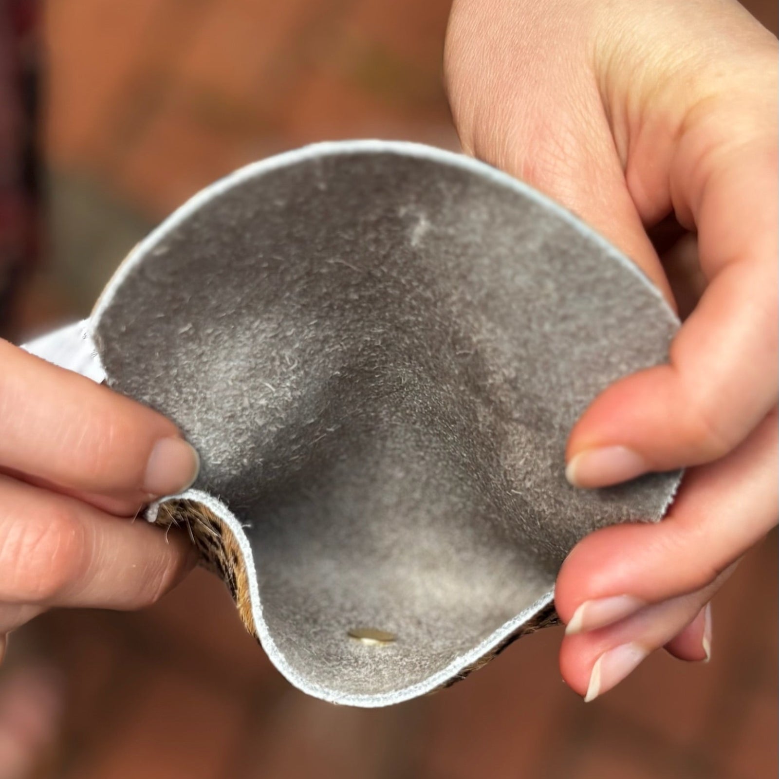 Someone holding the Tiny Spotted Hair on Hide Cardholder open to show the inside.