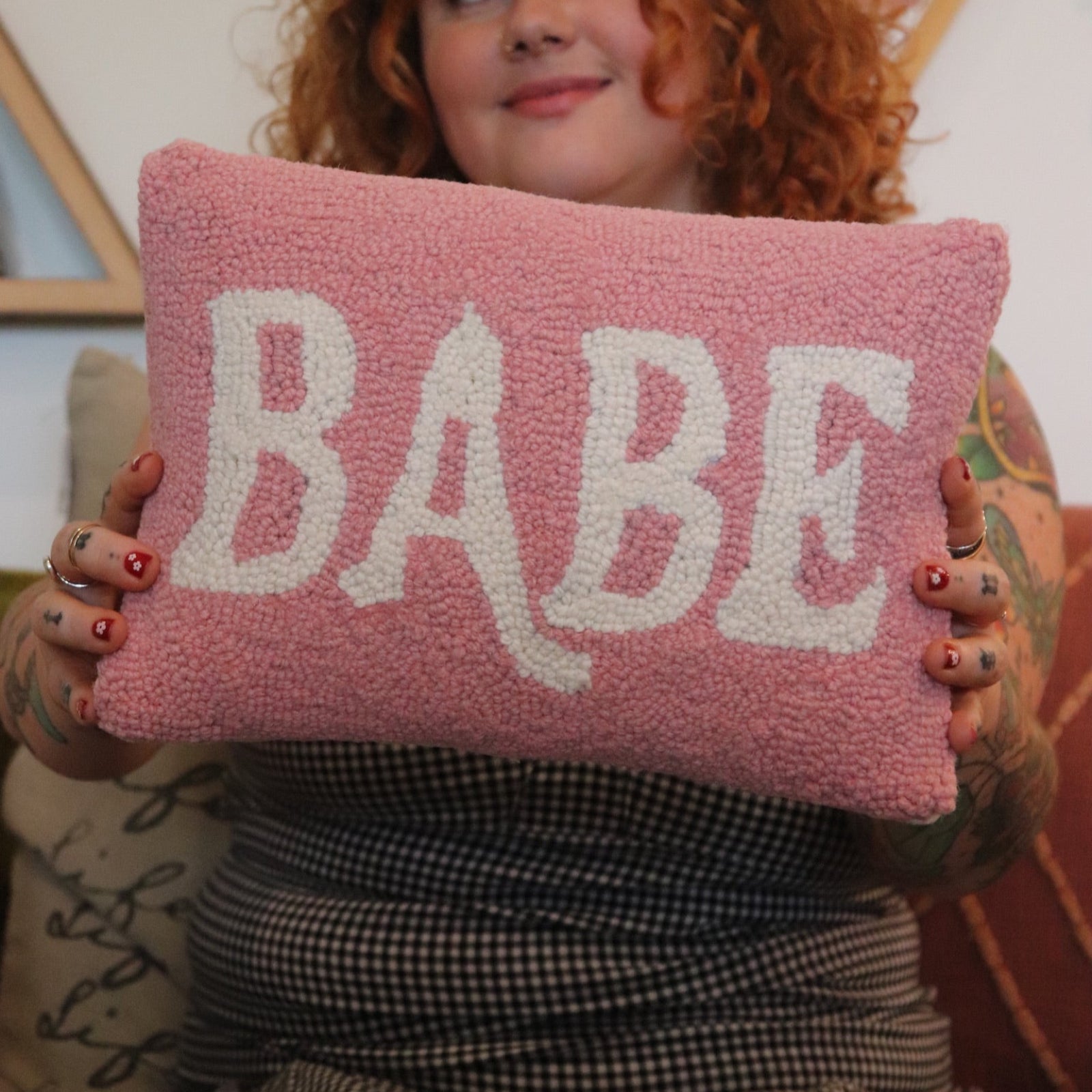 A woman holding the Babe Wool Hook Pillow.