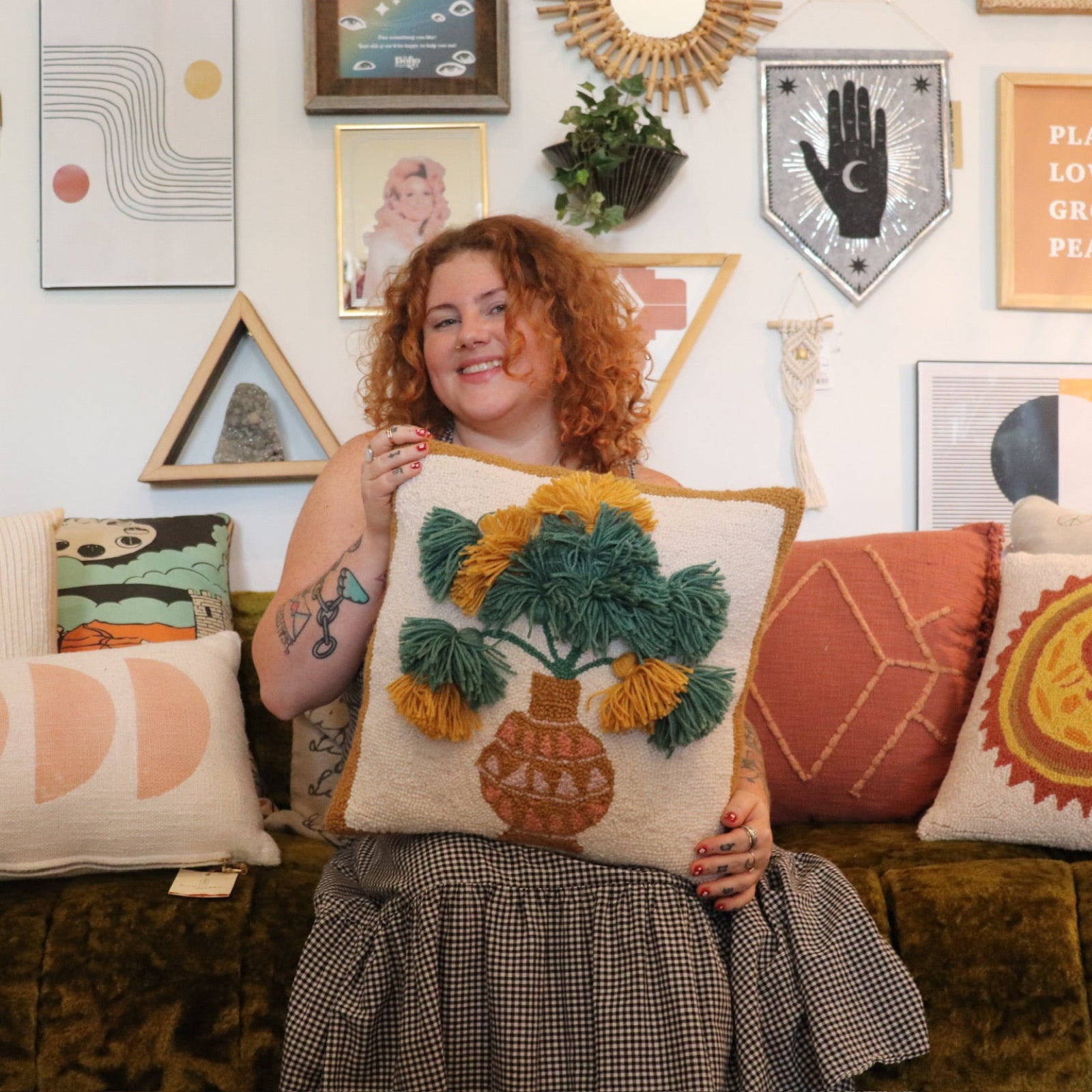 A woman holding the Papyrus Wool Hook Pillow.