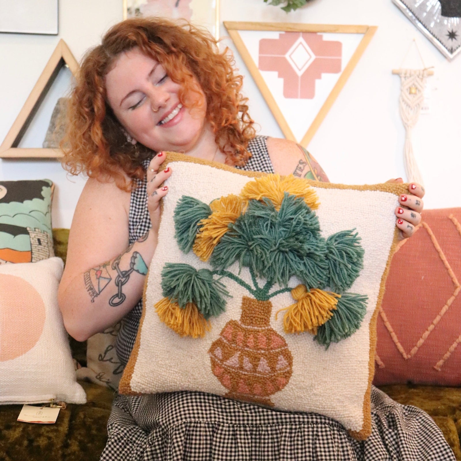 A woman holding the Papyrus Wool Hook Pillow.