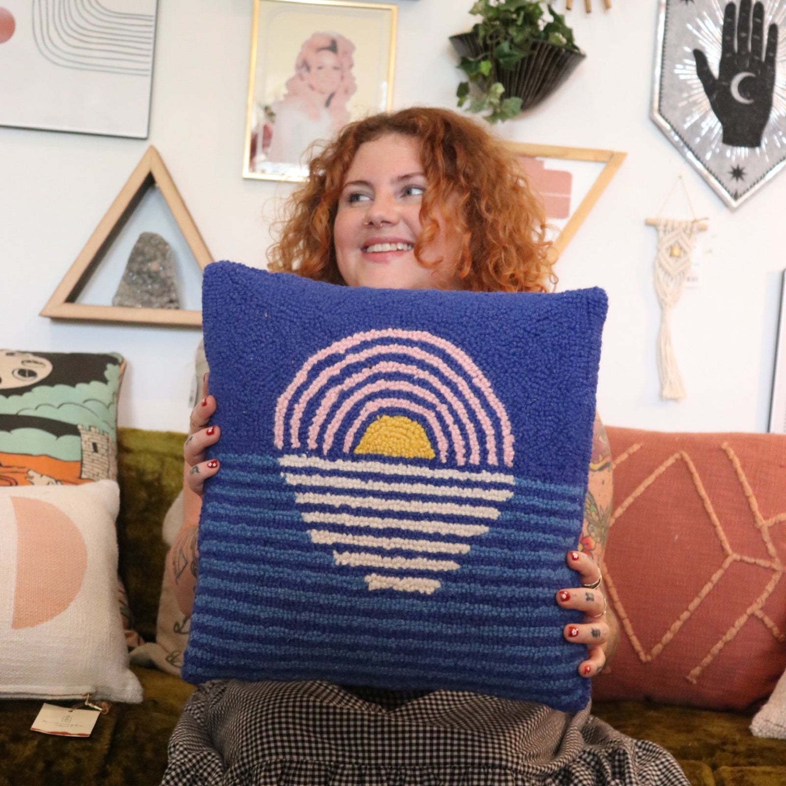 A woman holding the Blue Sunset Hook Pillow.
