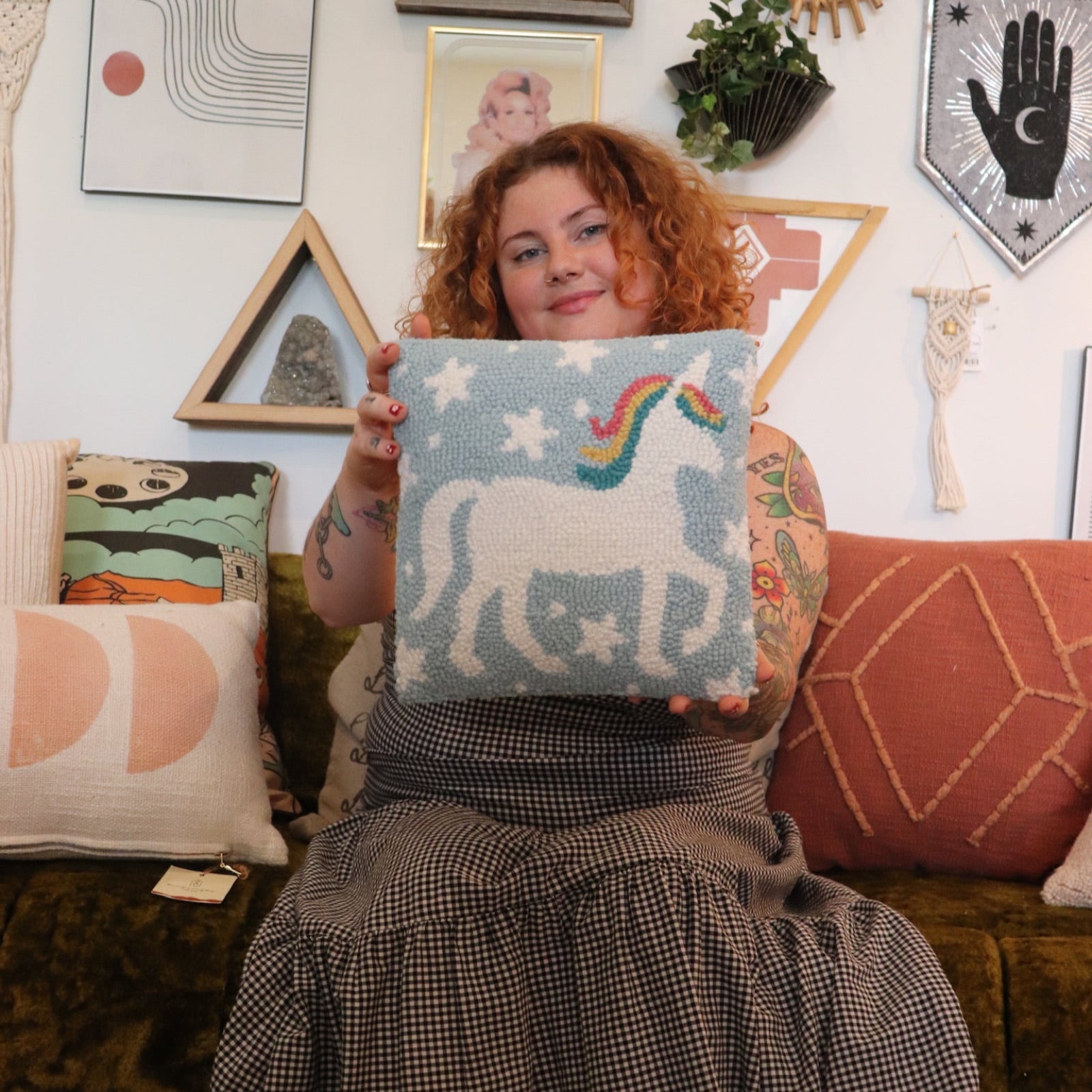 A woman holding the Unicorn Magic Wool Hook Pillow.