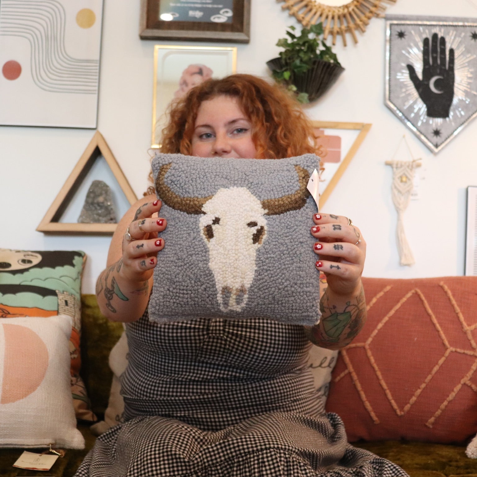 A woman holding the Cow Skull Wool Hook Pillow.