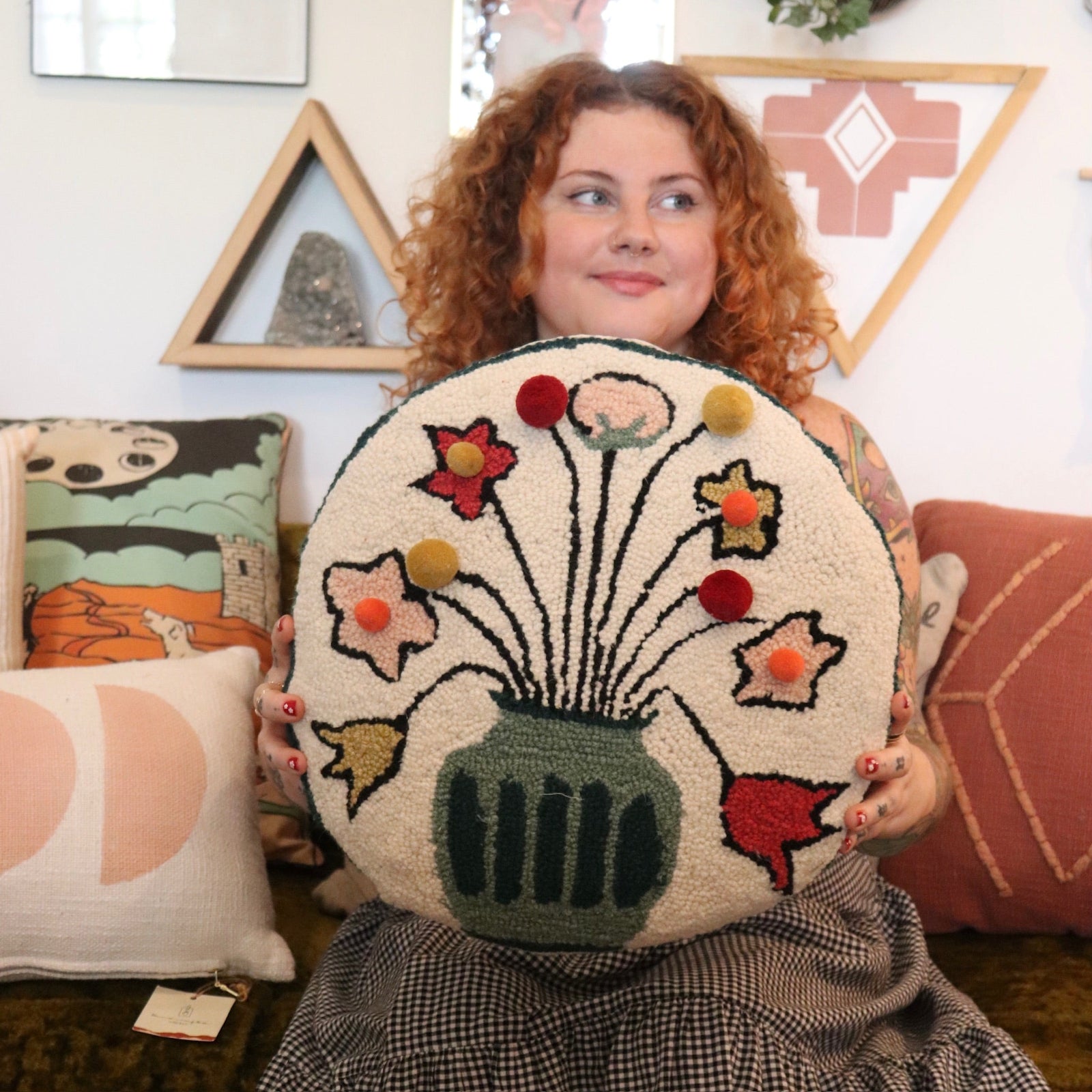 A woman holding the You Deserve Some Flowers Wool Hook Pillow with Pom Poms.