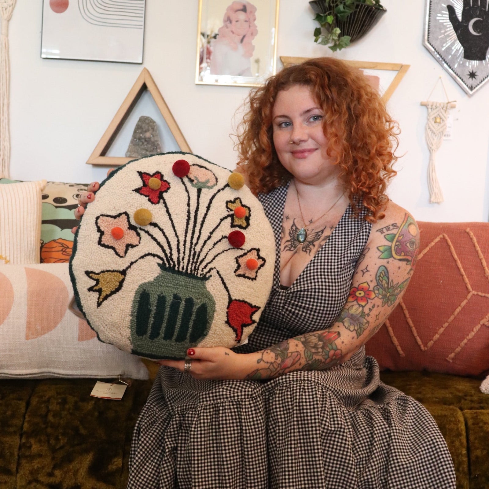 A woman holding the You Deserve Some Flowers Wool Hook Pillow with Pom Poms.