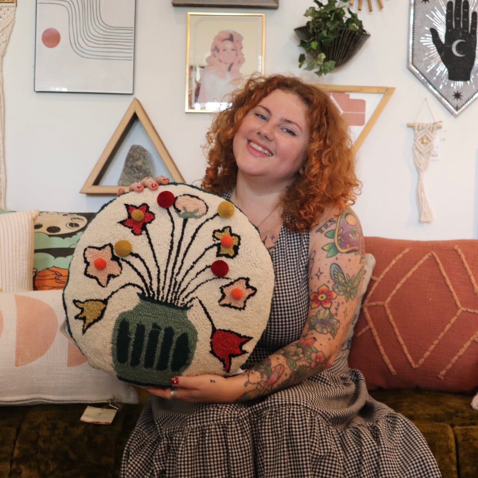 A woman holding the You Deserve Some Flowers Wool Hook Pillow with Pom Poms.