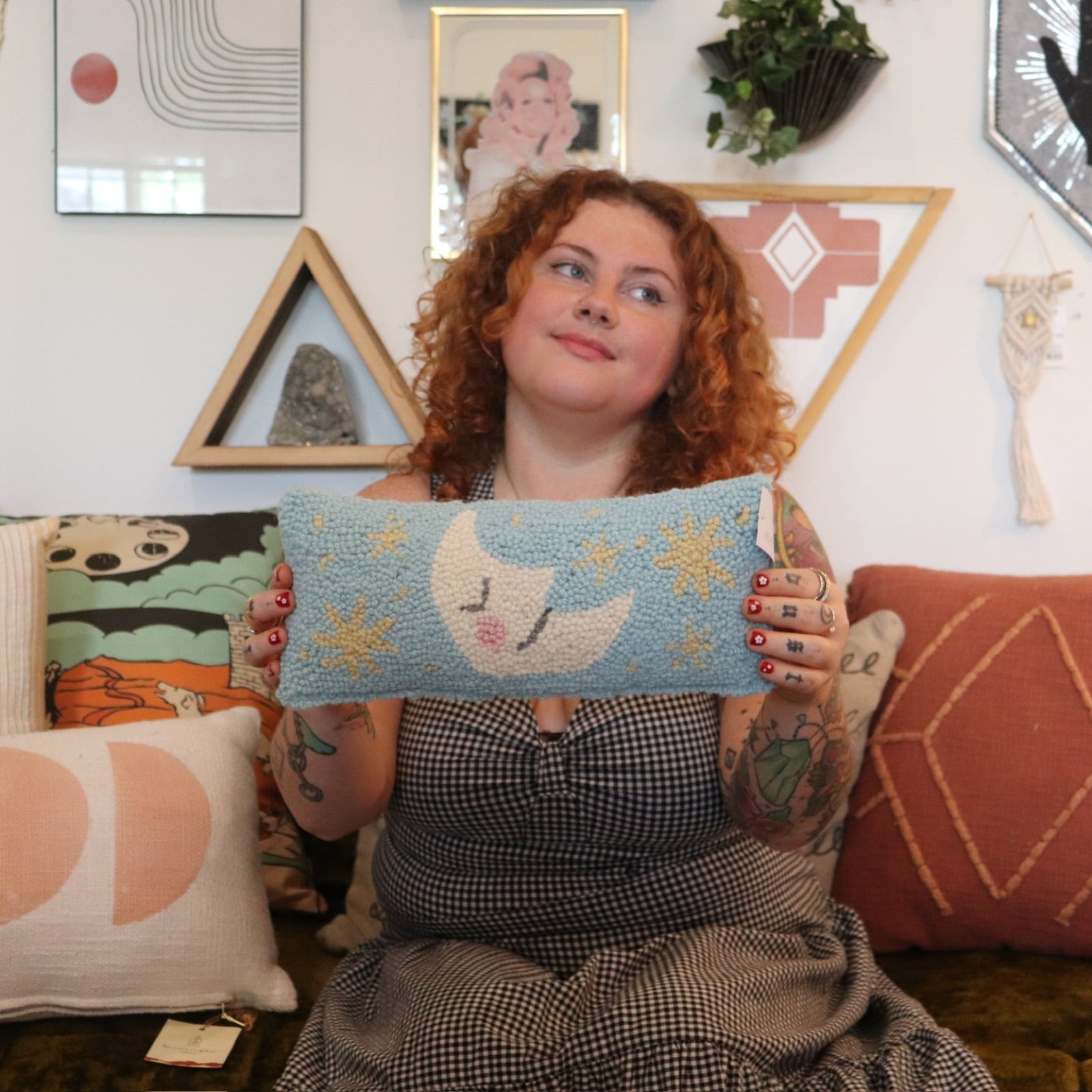 A woman holding the Moon And Stars Wool Hook Pillow.