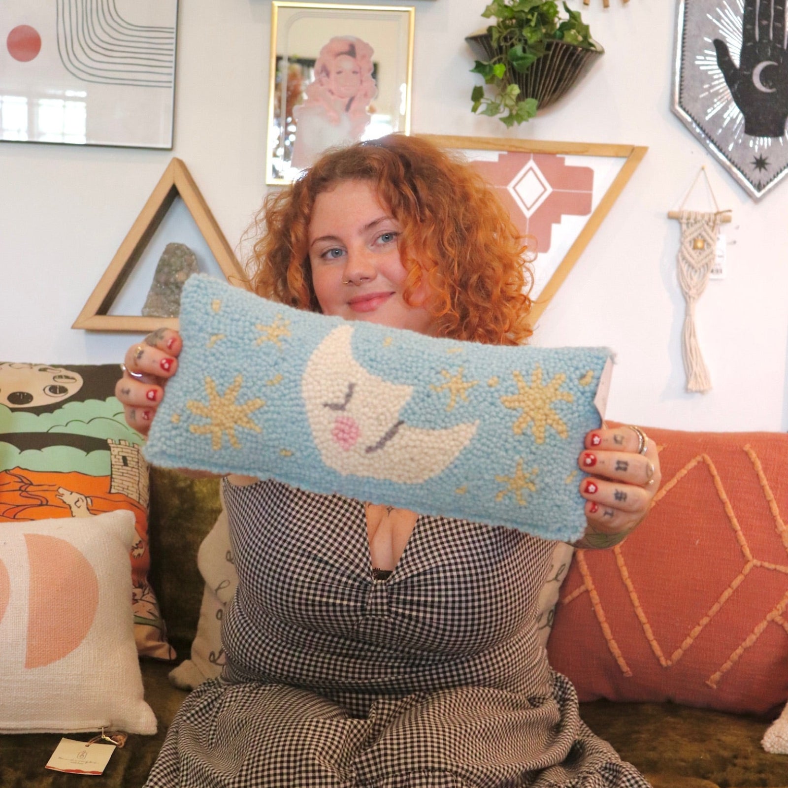 A woman holding the Moon And Stars Wool Hook Pillow.